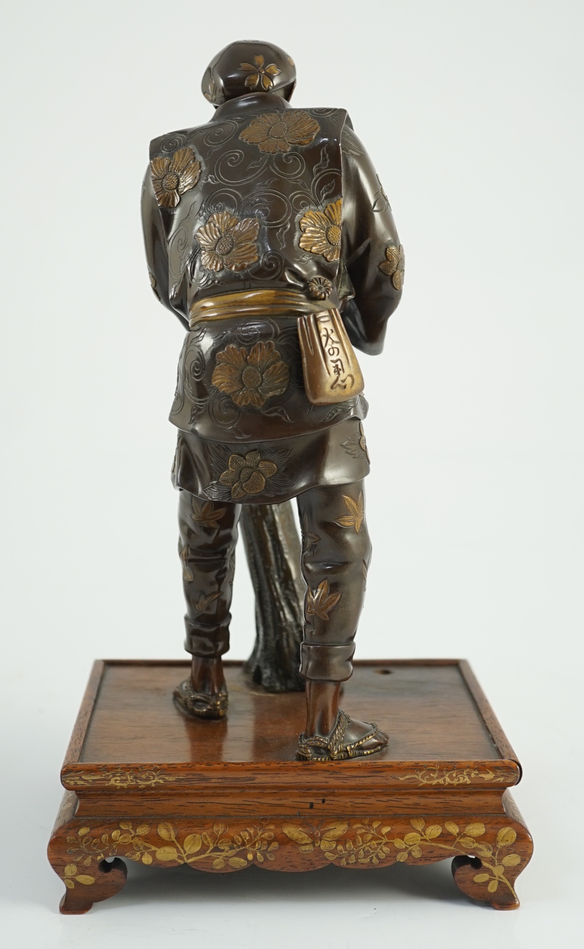 A Japanese brown patinated and gilded bronze figure of a woodworker, in Miyao style, Meiji period, 27.5cm high